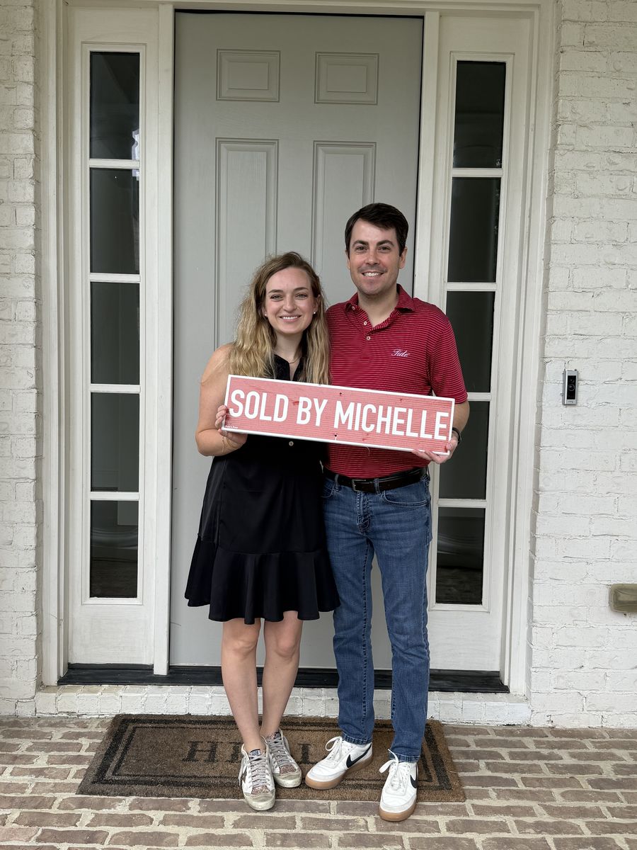 Michelle&rsquo;s clients holding a Sold by Michelle sign at a front door