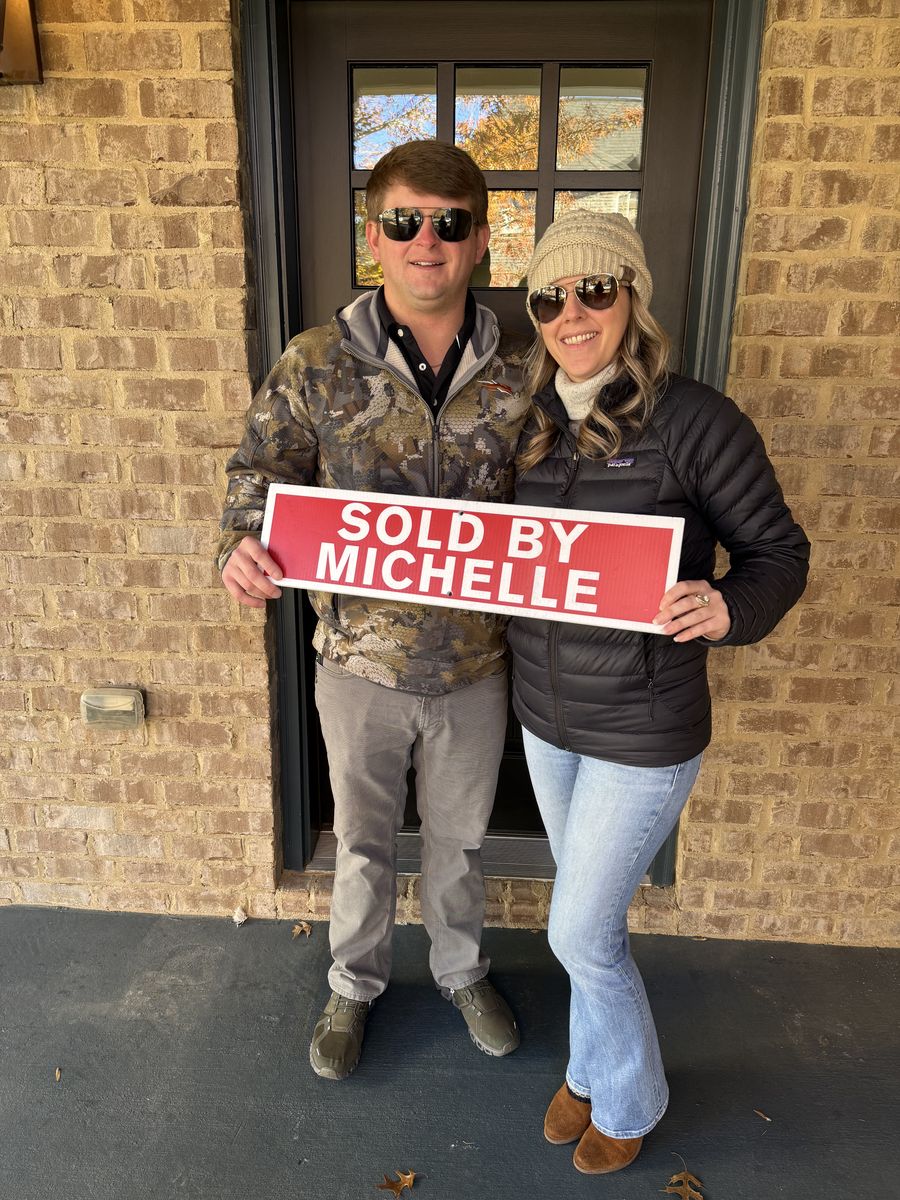 Michelle&rsquo;s clients holding a Sold by Michelle sign outside their home