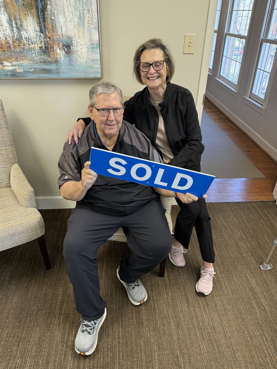 Michelle&rsquo;s clients holding a Sold sign inside a home