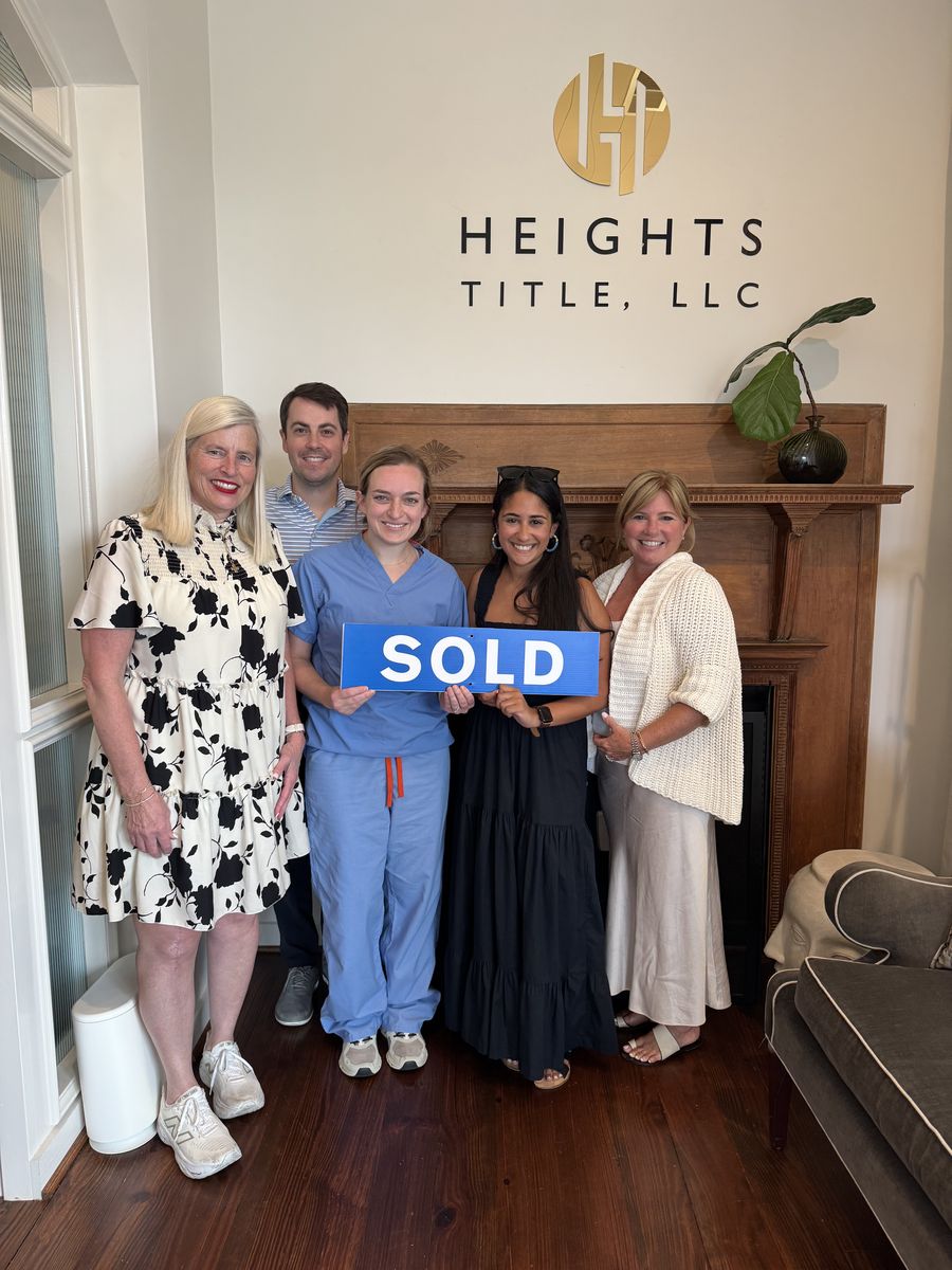 Michelle&rsquo;s clients holding a Sold sign at the closing office